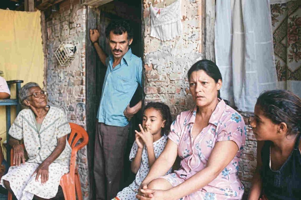 Cena do filme Narradores de Javé com moradores na frente de uma casa de tijolos no sertão